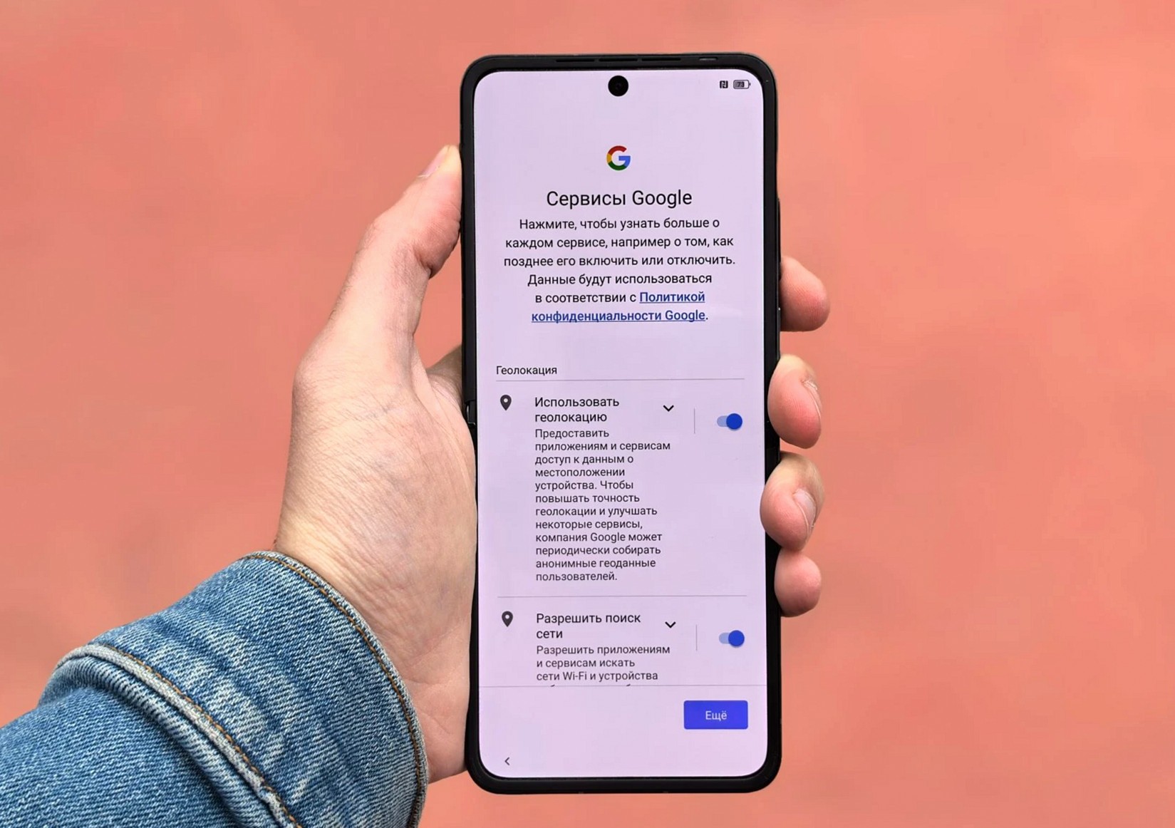 シンプルな背景の前でGoogleの設定画面を表示したスマートフォンを持つ人物